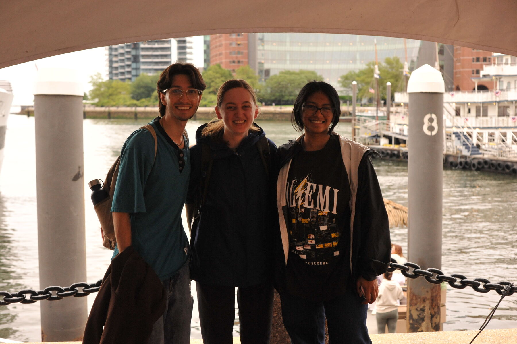 Three summer interns smiling on a Boston harbor pier