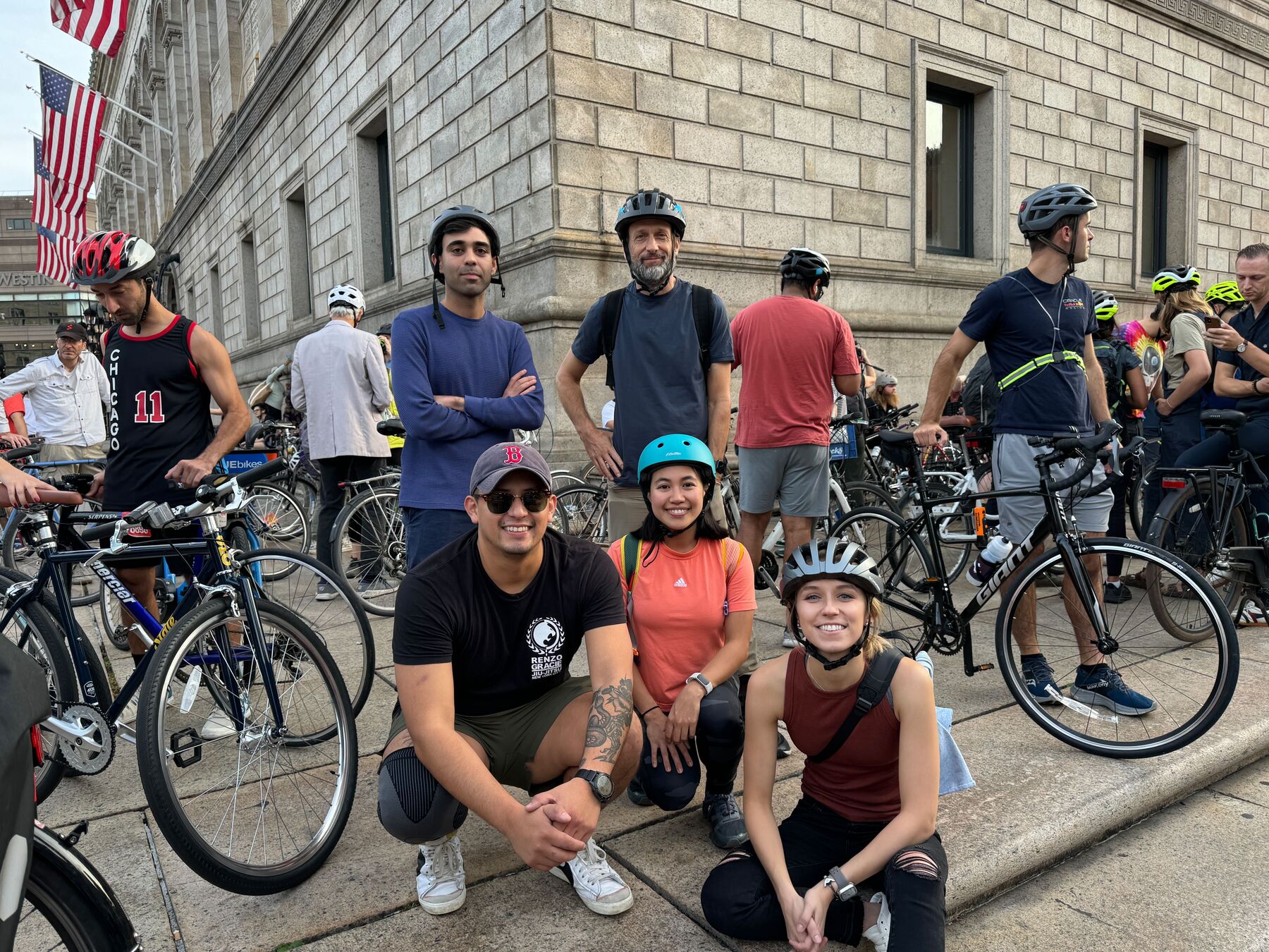 A group of teammates with their bikes and helmets on a city sidewalk