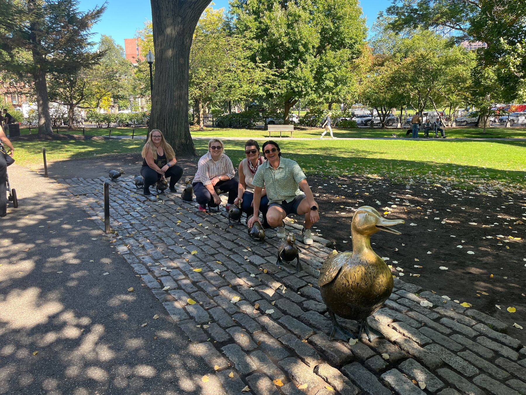 Teammates crouching beside the Make Way for Ducklings statues in the Boston Public Garden